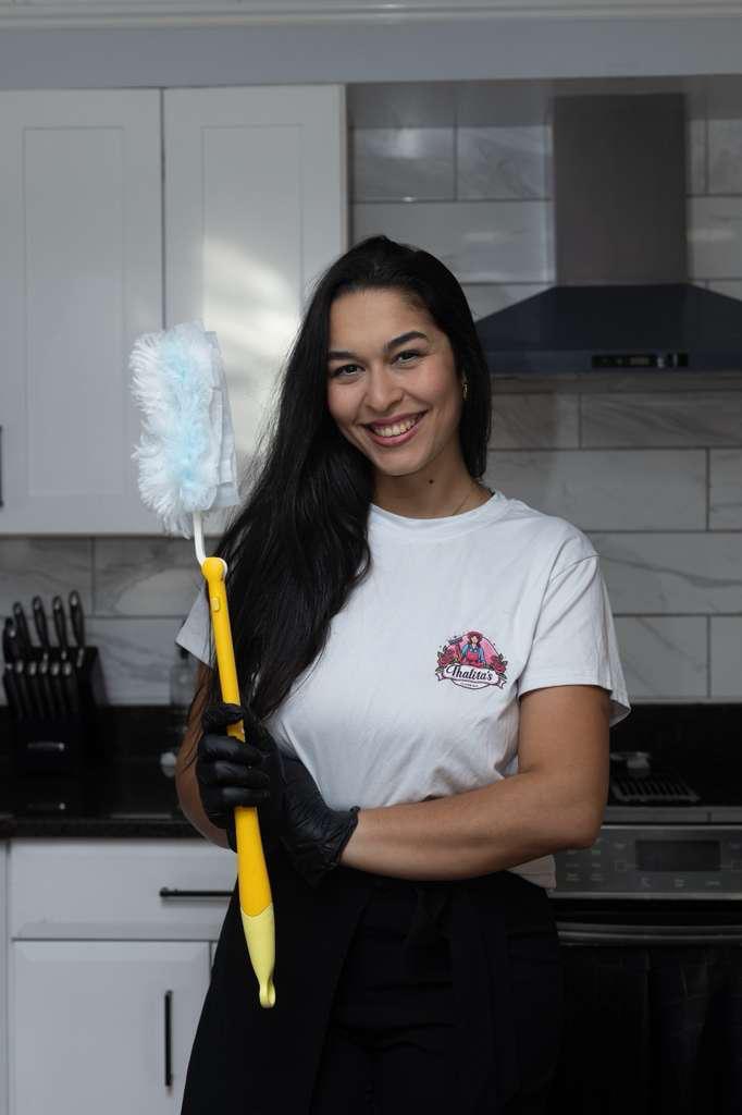 Professional cleaner from Thalita’s Cleaning smiling and holding cleaning tools